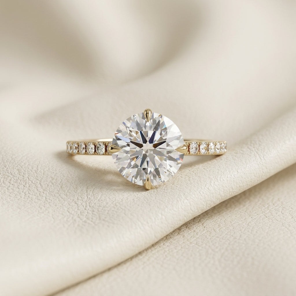 Round brilliant lab grown diamond solitaire engagement ring in 14K yellow gold
2.67 ct round diamond center held in a four-prong setting above a pavé band
Yellow gold pavé engagement ring with IGI certified round center stone
Classic round solitaire ring with sparkling pavé shoulders on a white background