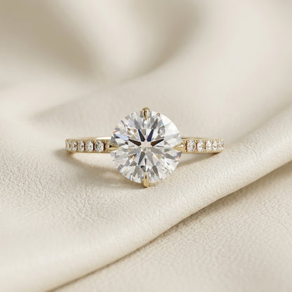 Round brilliant lab grown diamond solitaire engagement ring in 14K yellow gold
2.67 ct round diamond center held in a four-prong setting above a pavé band
Yellow gold pavé engagement ring with IGI certified round center stone
Classic round solitaire ring with sparkling pavé shoulders on a white background