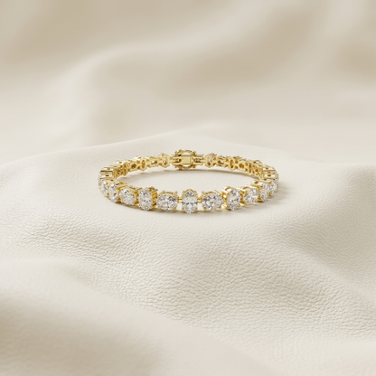Oval lab grown diamond tennis bracelet in yellow gold with elegant four-prong settings.
